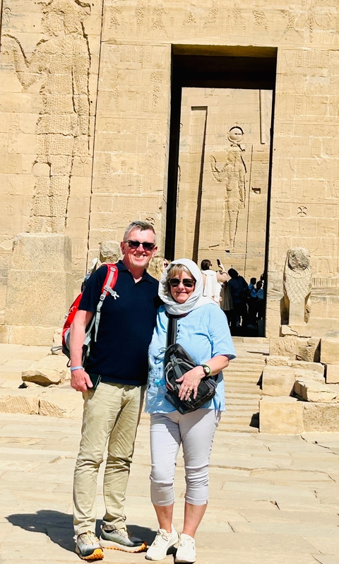       Tourists posing in front of hieroglyphic-covered ancient temple.
  
