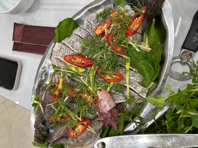 Platter of fish and vegetables garnished with herbs.