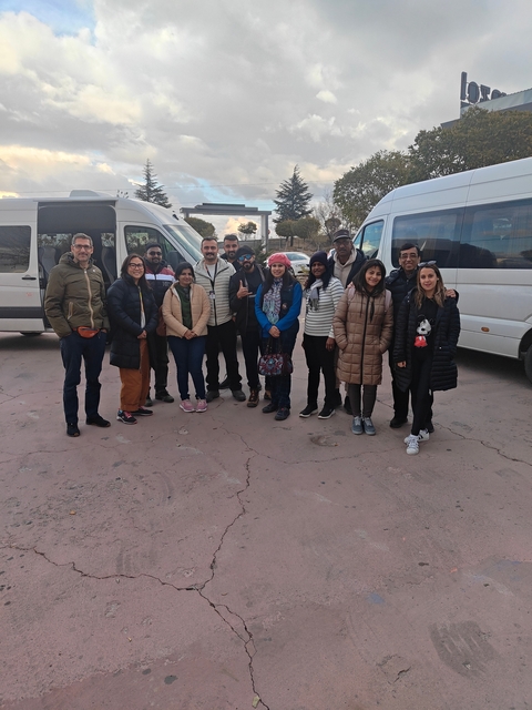 Group of people posing in front of tour buses.