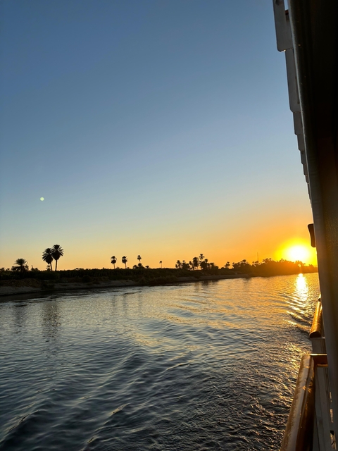 River at sunset with palm trees silhouette.