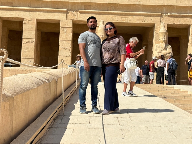 Couple posing in front of an ancient temple with statues.