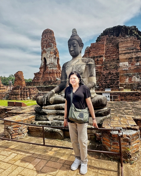 A person standing in front of a large Buddha statue.