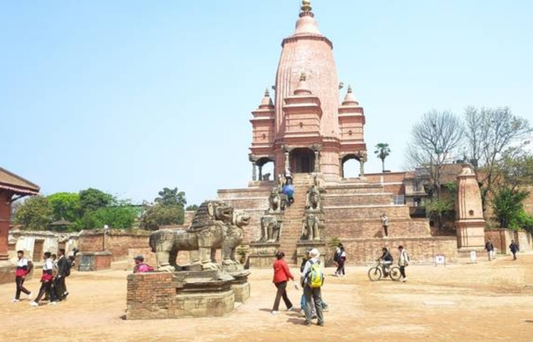 People walking around a historical temple with statues.