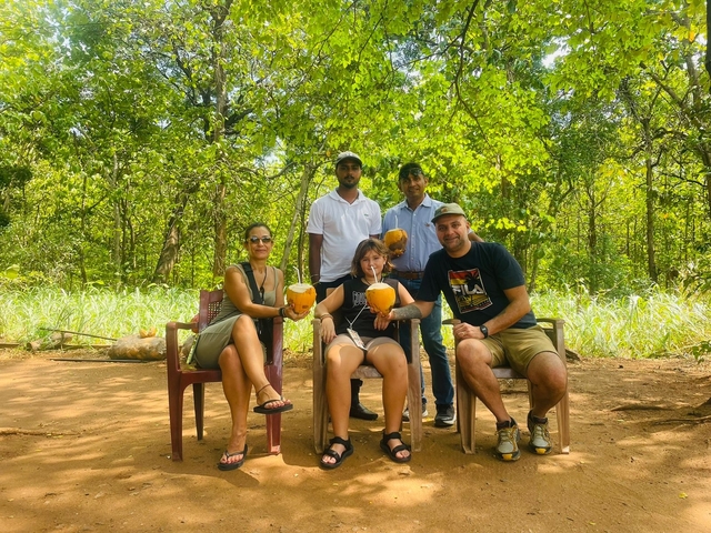 Group of people enjoying coconuts in a shady area.