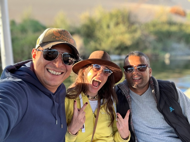 Three people smiling broadly with a river backdrop.