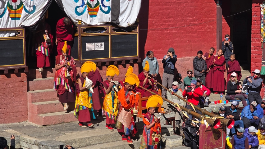       Traditional dance performance with monks and tourists watching.
  
