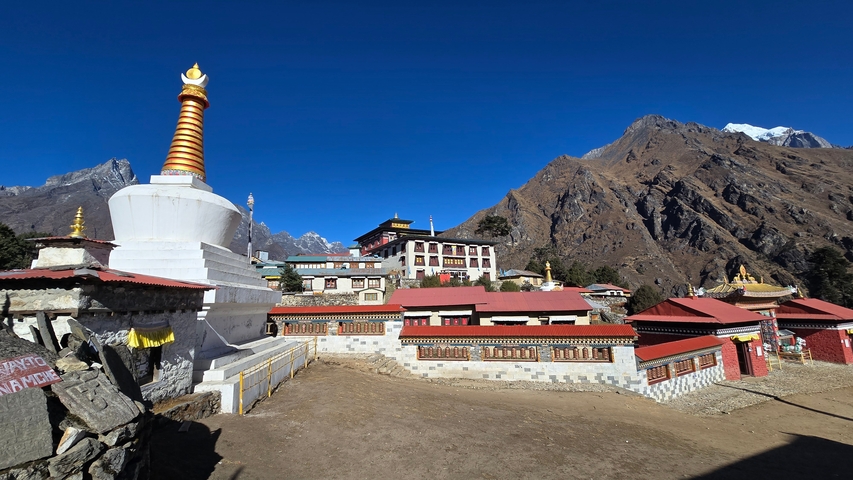 Buddhist monastery with a stupa and mountain backdrop.