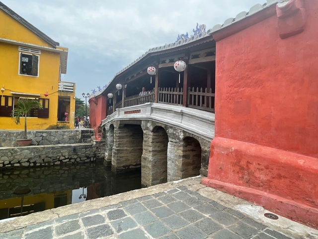       Japanese covered bridge with yellow and red buildings.
  