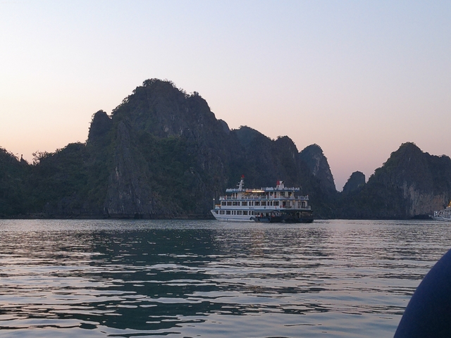       Cruise ship on the water with limestone cliffs.
  
