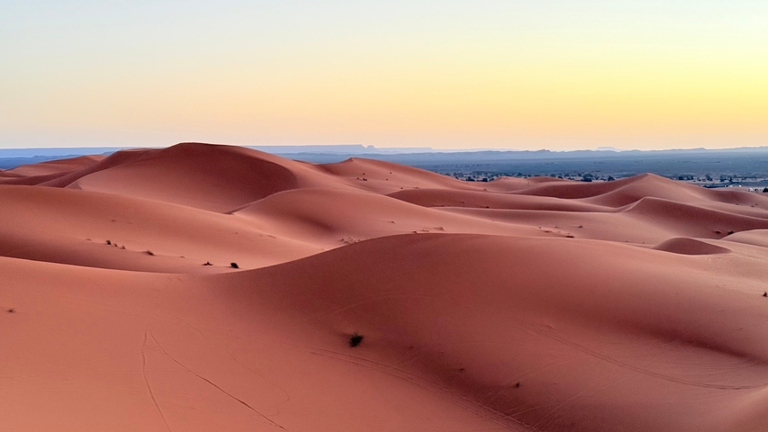       Sunset over rolling sand dunes.
  