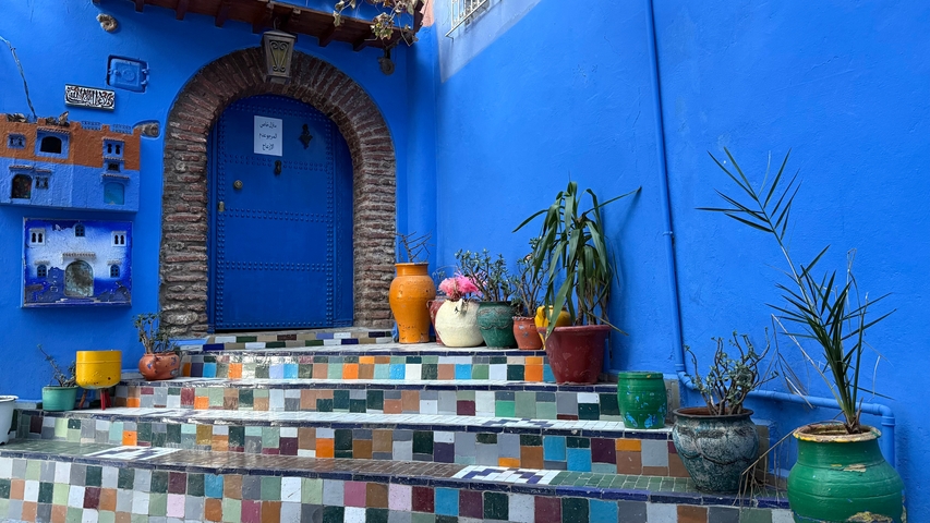 Colorful steps with pots leading to a blue door.