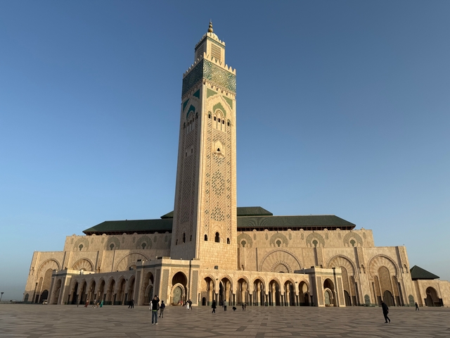       Large mosque with a tall minaret at sunset.
  