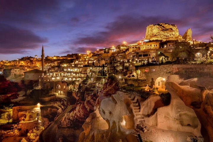 Evening skyline of Cappadocia with illuminated caves and sky.