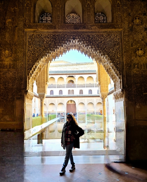       A person standing in a historic palace courtyard with intricate arches.
  