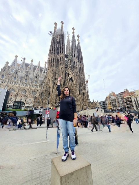       A person posing in front of the Sagrada Familia in Barcelona.
  