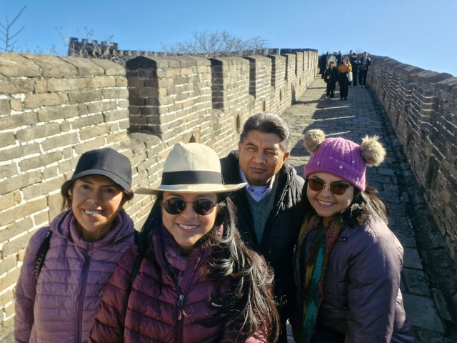 People walking atop a stone fortification wall under clear skies.