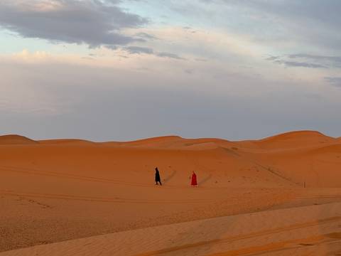      Couple walking through sand dunes.
  