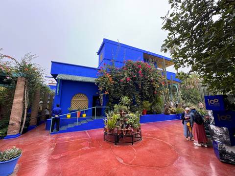       Blue building with plants and a man in the foreground.
  