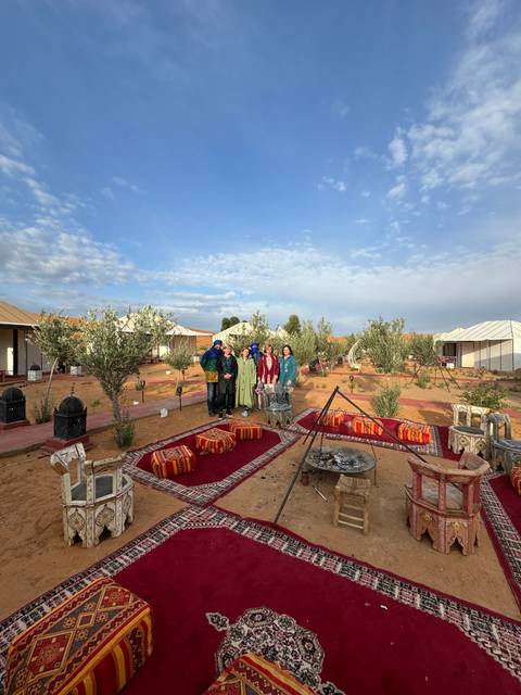       Group sitting by a campfire outside tents.
  