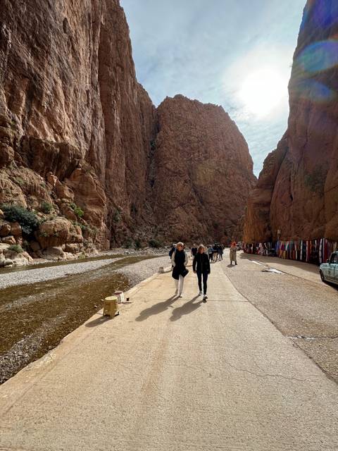       Narrow canyon with market stalls and people.
  