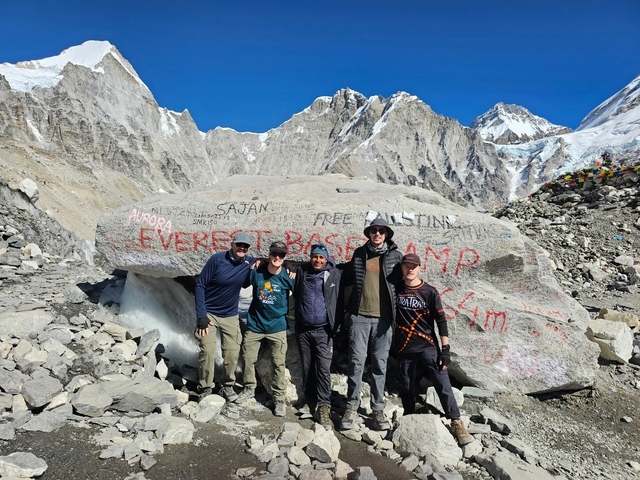 Group of hikers posing at the Everest Base Camp landmark.