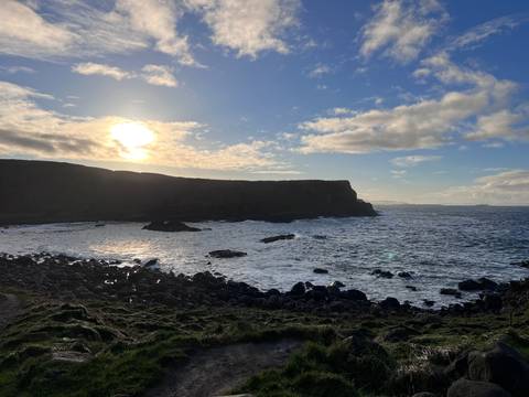 Sunset over a rocky coastline with rough seas.