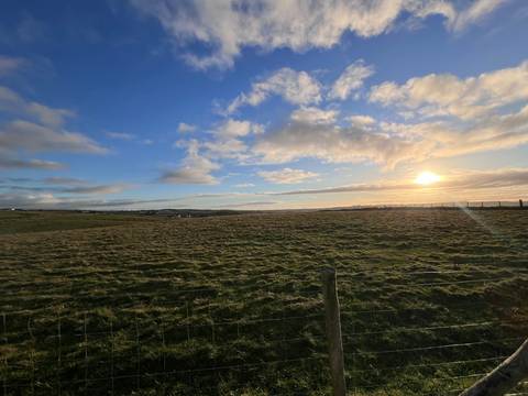 Open fields under a dramatic sky during sunset.