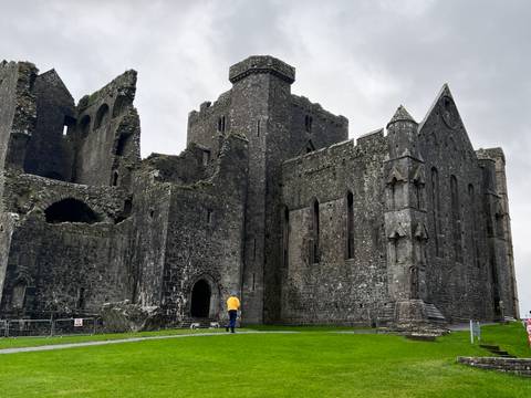 A man standing in front of the historically significant Rock of Cashel.