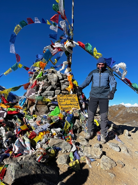 A hiker at Surya Kunda Pass with prayer flags.