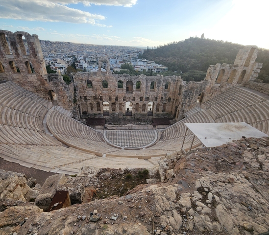      View of Herodion Theatre with city in background.
  