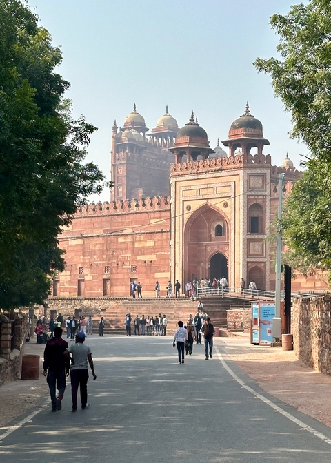 Group of tourists outside a historic fort with red sandstone architecture.