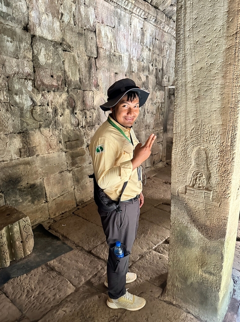Person posing inside an ancient temple with carvings on the walls.