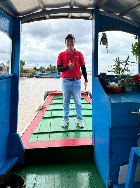 Person standing on a colorful boat on a river.