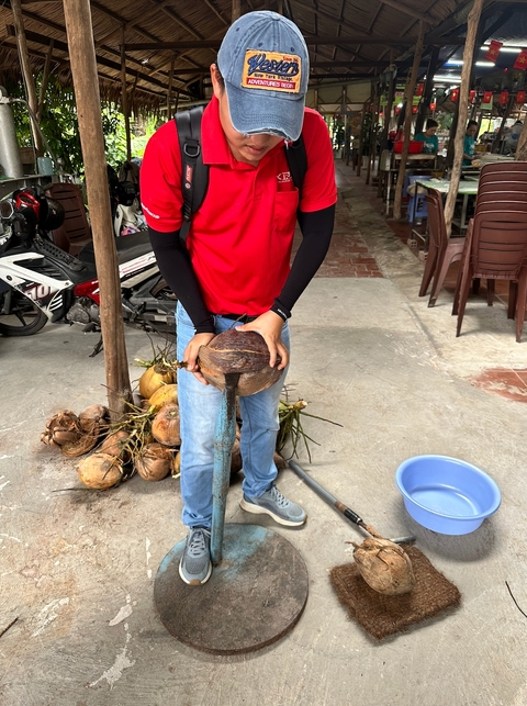 Person holding a split coconut in a traditional setting.