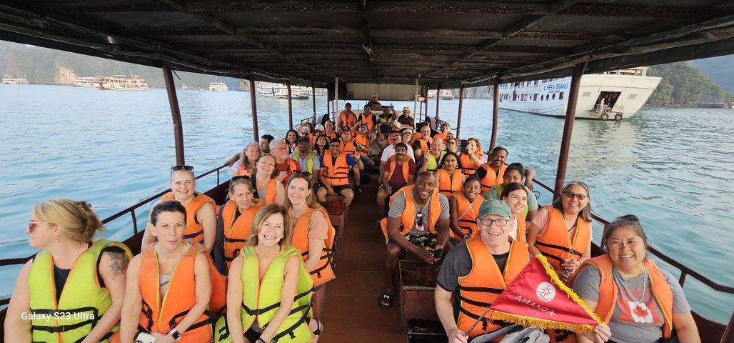 A large group of people in life vests on a boat excursion.