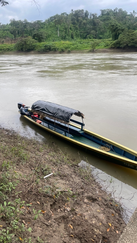       A small boat docked on the shore of a river.
  