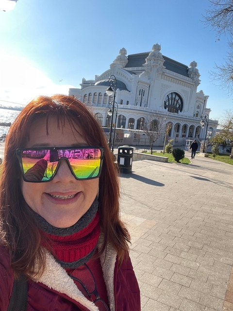 Close-up of a woman wearing sunglasses outside a white building.