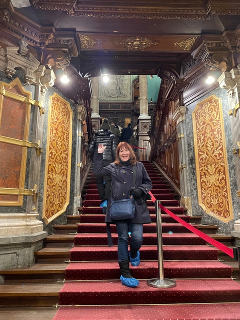 People on a grand staircase in a decorative interior.