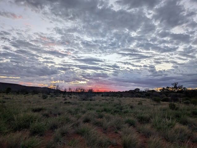       Sunset with a dramatic cloudy sky over a field.
  