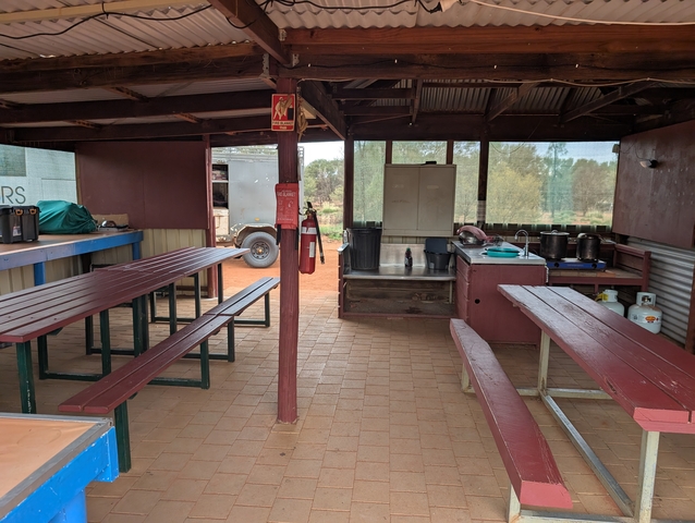       Interior of a simple dining area with benches and tables.
  