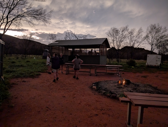 Group of people by a rustic cabin in the evening.