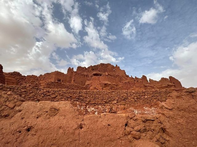 Remains of a mud-brick fortress against a cloudy sky.