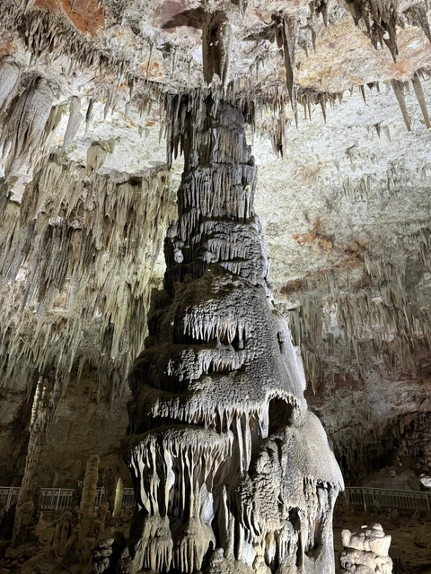 Cave with stalactites and stalagmites forming intricate patterns.