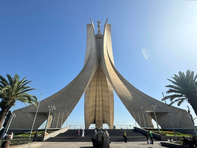 A tall concrete monument with palm trees.