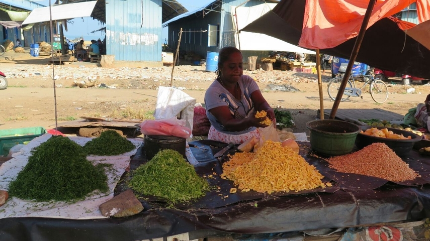 Market scene with goods displayed on a table and a vendor.