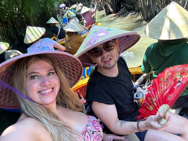 A group of people in a boat with traditional hats rowing through a canal.