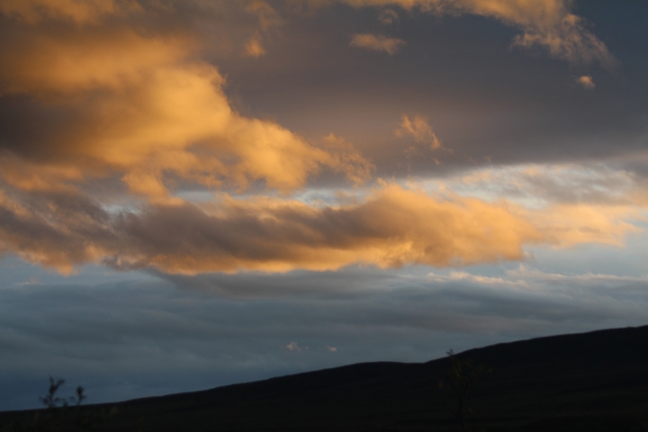       Colorful clouds against a dark skyline at sunset.
  