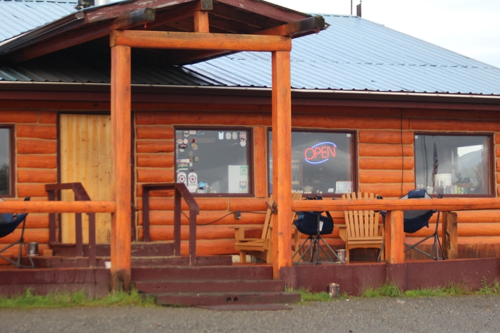       A wooden cabin with an 'OPEN' sign and outdoor seating.
  