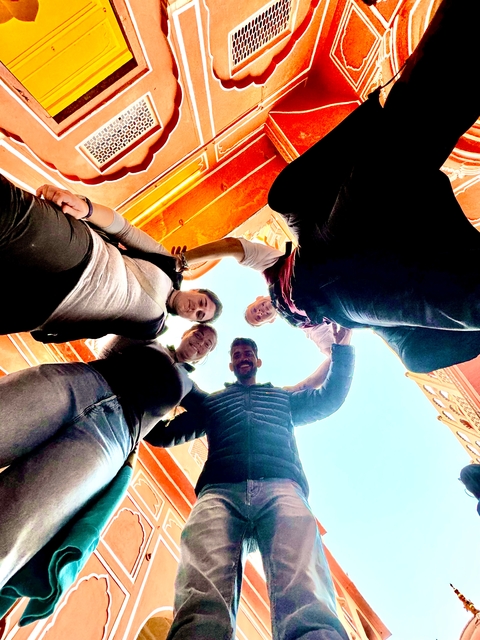 Friends posing in a circular formation under an archway.