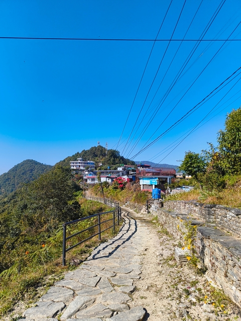 Path leading through a village with mountainous backdrop.